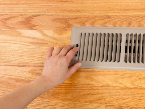 Woman opening a floor vent in a Belchertown home