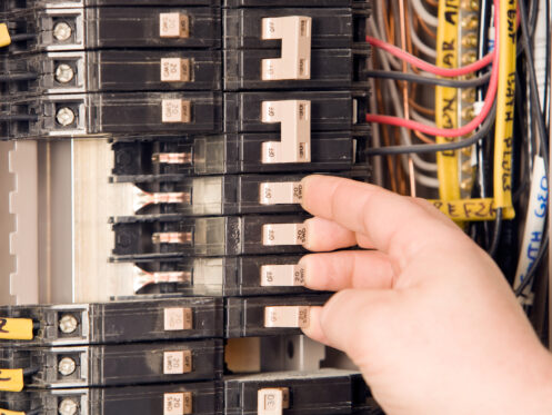 Electrician’s Hand Turning On Circuit Breakers in Belchertown