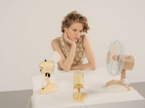 woman sits in front of three tabletop fans